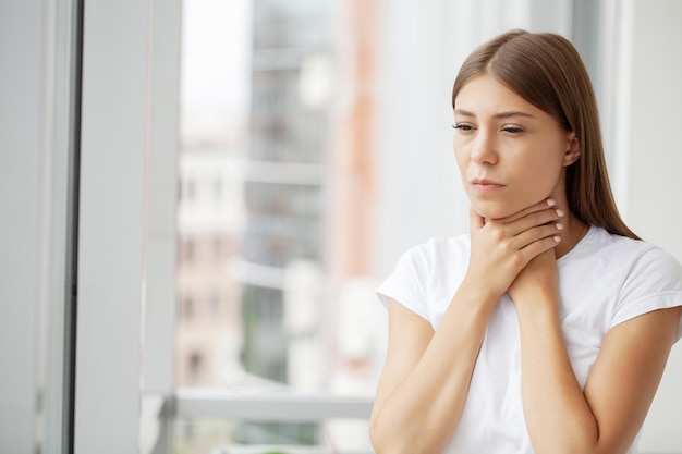 Giovane donna che si sente esausta e soffre di dolore al collo concetto di salute