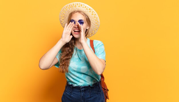 Young woman feeling happy, excited and positive, giving a big shout out with hands next to mouth, calling out