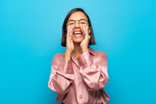 Giovane donna che si sente felice, eccitata e positiva, dando un grande grido con le mani vicino alla bocca