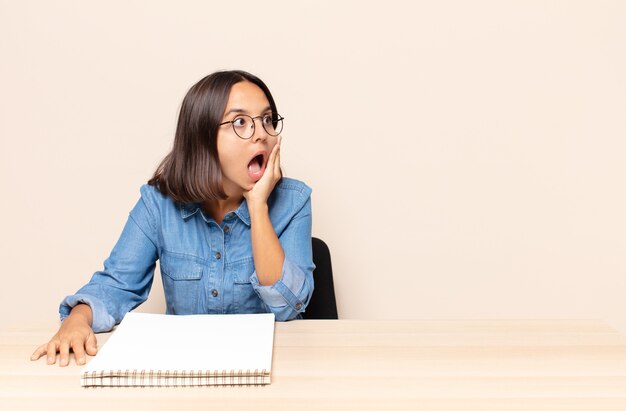 Young woman feeling happy, excited and surprised, looking to the side with both hands on face