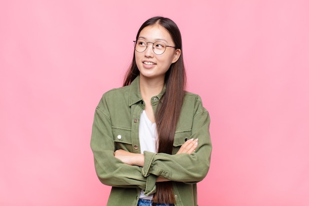 Young woman feeling happy, proud and hopeful, wondering or thinking