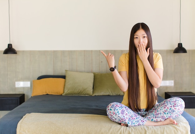 幸せ、ショック、驚きを感じ、手で口を覆い、指さしている若い女性