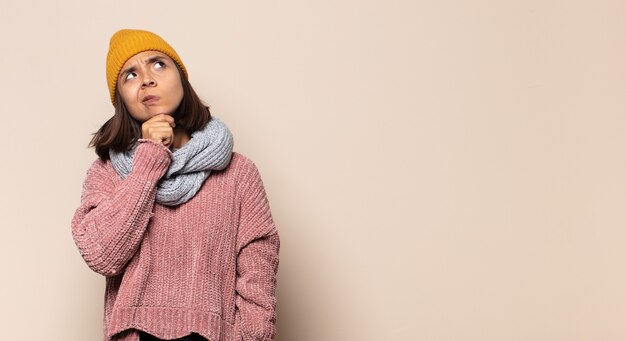 Young woman feeling happy and smiling casually, looking to an object or concept held on the hand on the side