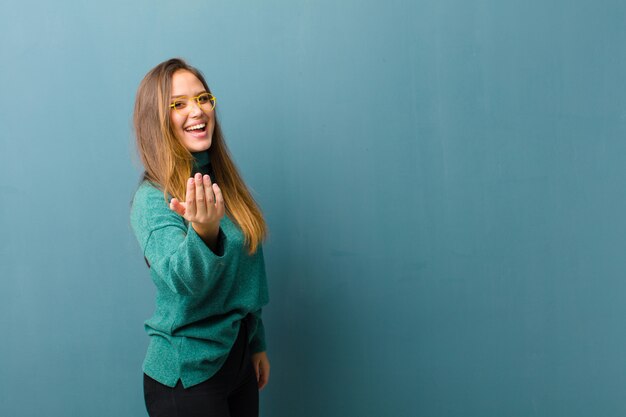 Photo young woman feeling happy, successful and confident, facing a challenge and saying bring it on! or welcoming you