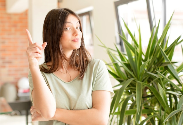 Young woman feeling like a genius holding finger proudly up in the air after realizing a great idea saying eureka