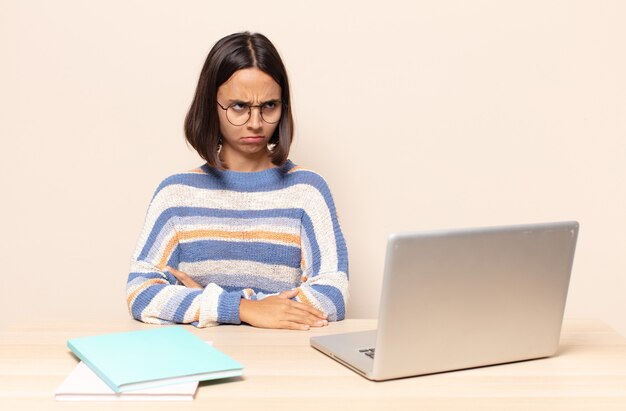 Young woman feeling sad, upset or angry and looking to the side with a negative attitude, frowning in disagreement