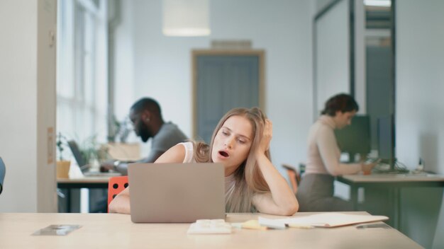 写真 コワーキングで眠気を感じる若い女性