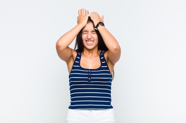 Young woman feeling stressed and anxious, depressed and frustrated with a headache, raising both hands to head