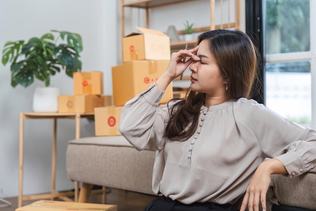 配送箱に囲まれた自宅からオンライン販売を管理している若い女性がストレスを感じています