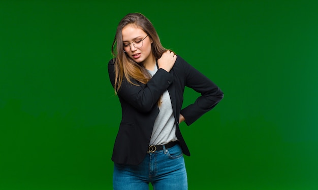 Young woman feeling tired, stressed, anxious, frustrated and depressed, suffering with back or neck pain on green