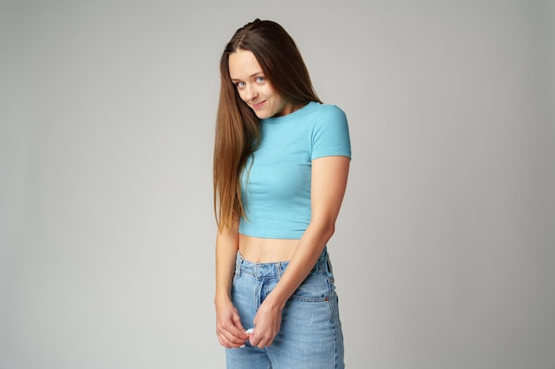 young woman feeling uncomfortable and shy on gray background