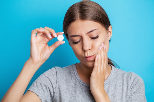 Una giovane donna sente mal di denti e tiene il posto del dolore con le mani