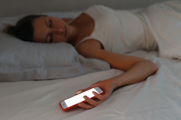 Young woman fell asleep with smartphone in her hand