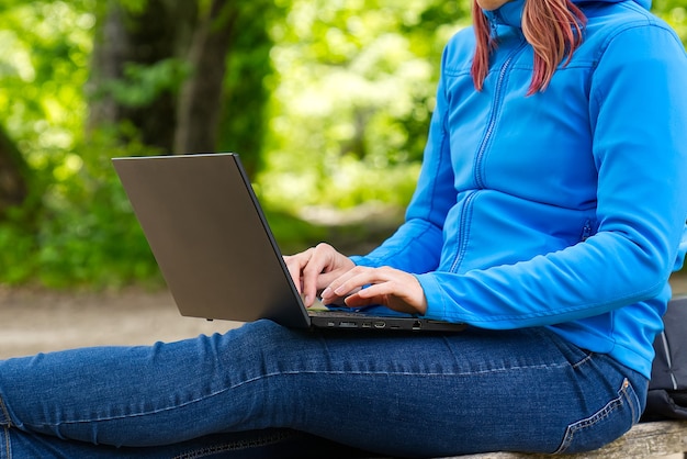 Young woman female freelancer working with laptop with beautiful view of forest and lake