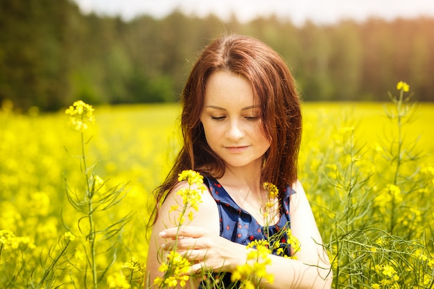 young woman in a field of rapeseed on a sunny day