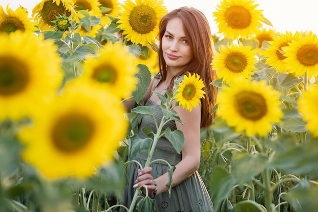 Young woman in a field with sunflowers in a green dress