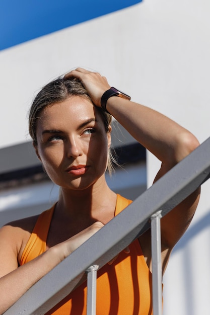 Young Woman Fitness Enthusiast Wearing an Orange Sports Bra Resting Outdoors