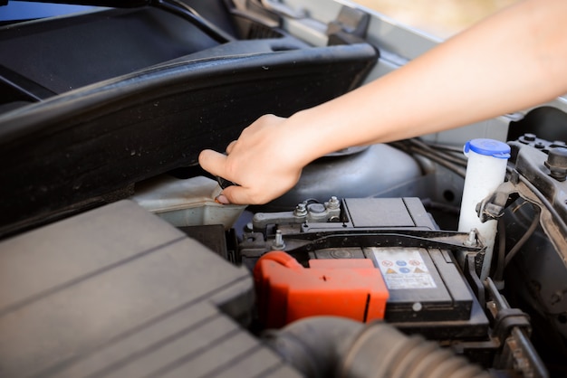 Young woman fixing car by a wayside because it suddenly broke down