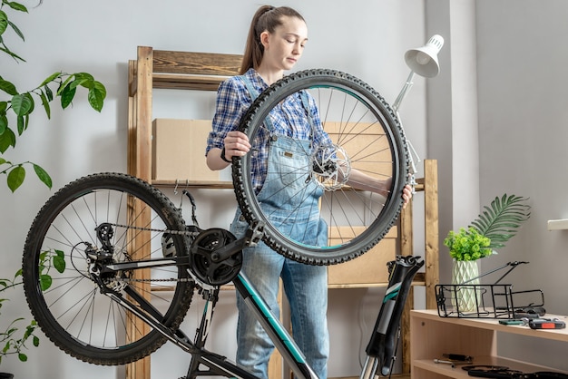 ワークショップでマウンテンバイクを修理する若い女性。新シーズンの準備、修理、メンテナンスのコンセプト