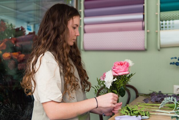 若い女性の花屋は職場で花を扱う中小企業のコンセプトライフスタイルトリミングされた肖像画の花をクローズアップ