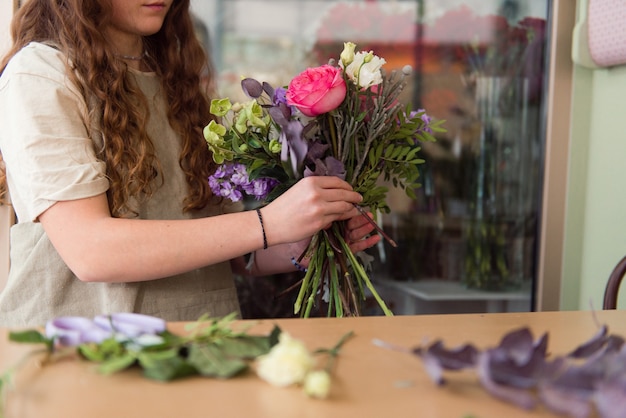 Fiorista di giovane donna lavora con fiori sul posto di lavoro concetto di piccola impresa stile di vita ritagliata ritratto fiori da vicino