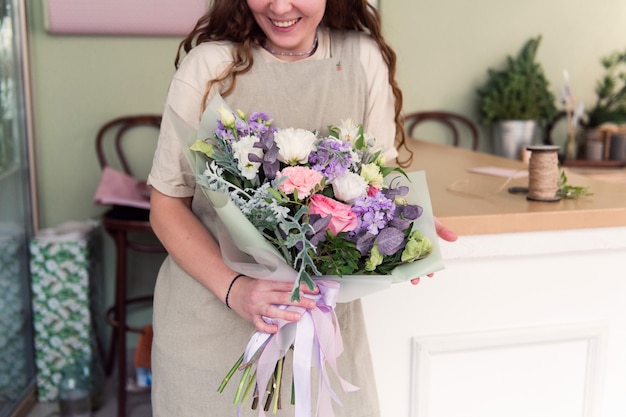 Young woman florist work with flowers at workplace small business concept lifestyle cropped portrait flowers close up