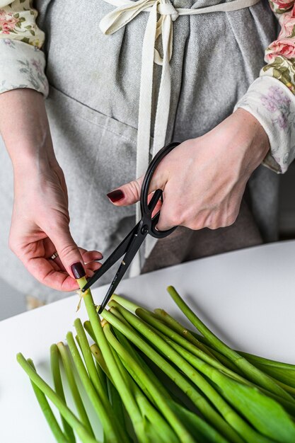 Young woman florist working with fresh flowers tulips, making bouquet