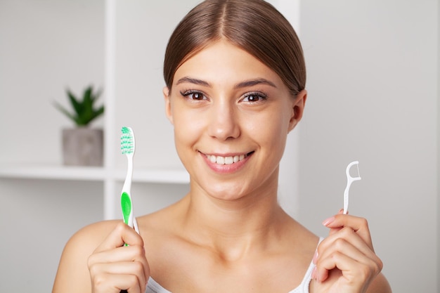 Photo young woman flossing her teeth in bathroom