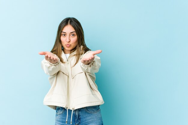 Young woman folding lips and holding palms to send air kiss