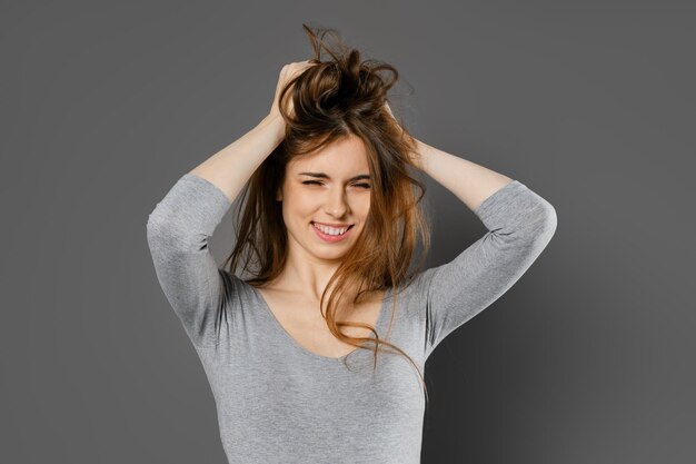 Foto giovane donna che si prende in giro e si pettina i capelli con le mani.