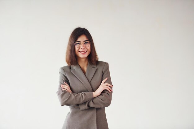 Young woman in formal clothes is standing against white background in the studio