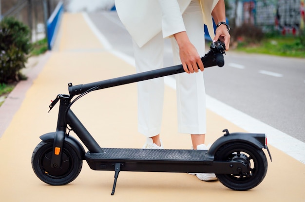 Young woman in formal wear folding electric scooter