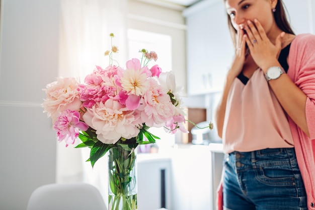 写真 若い女性が台所で牡丹の花束を見つけた幸せな興奮した女の子の笑顔