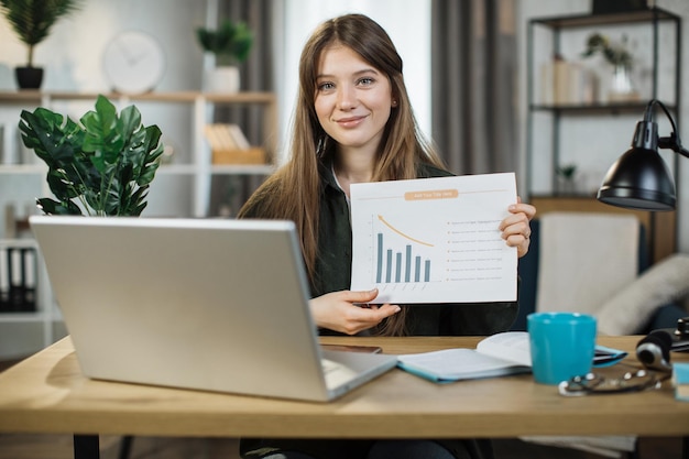 young woman freelance showing graphs and chart while sitting at table