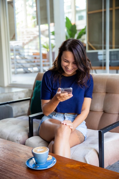 Young woman freelancer working with cellphone she sits at the table