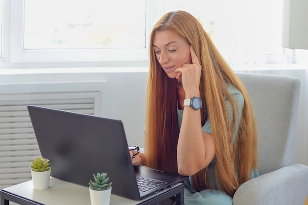 молодая женщина-фрилансер работает дома за ноутбуком онлайн-обучение