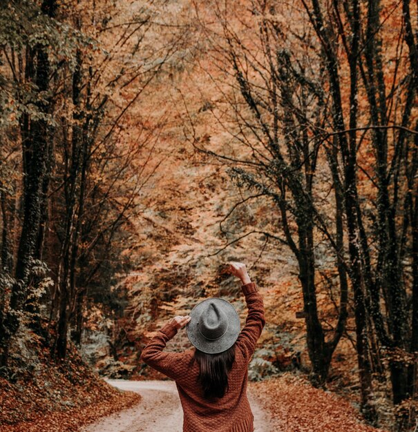 Photo young woman from behind on road in autumn fall forest