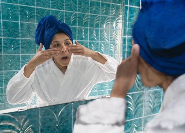 young woman in front of the mirror massaging her face