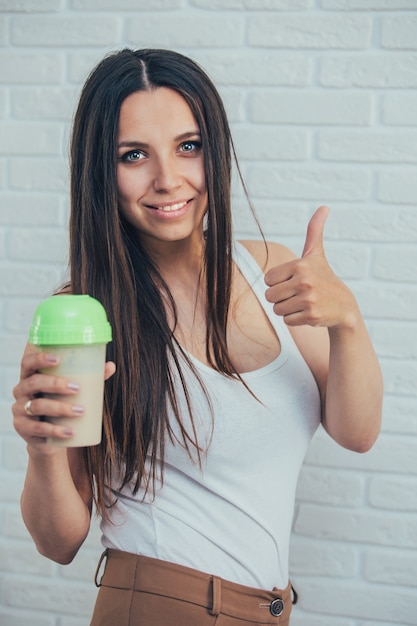 Young woman in front of a white brick wall with shaker