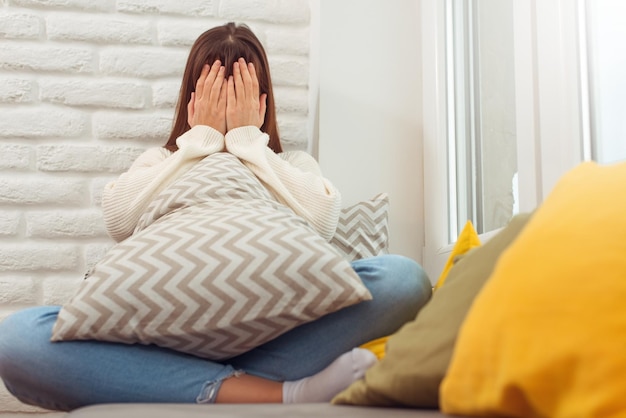 Young woman frustrated by problem with work or relationships\
sitting on couch