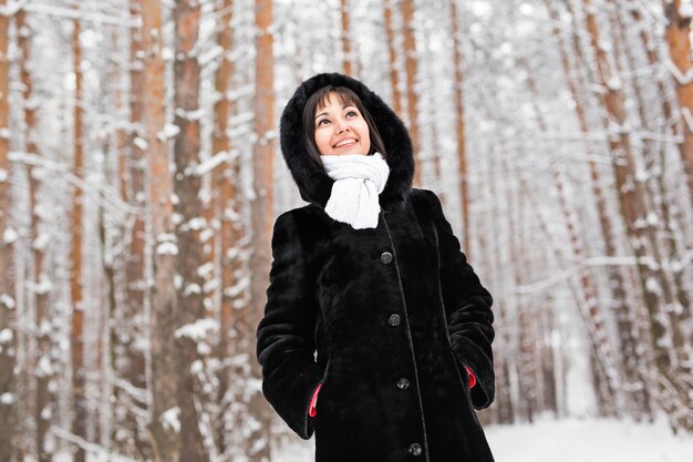 Young woman in fur coat outdoors in snow garden.