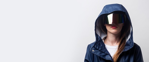 Giovane donna del futuro in occhiali per realtà virtuale in una giacca blu su sfondo chiaro banner