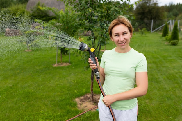 Young woman gardener watering fruit trees in the garden