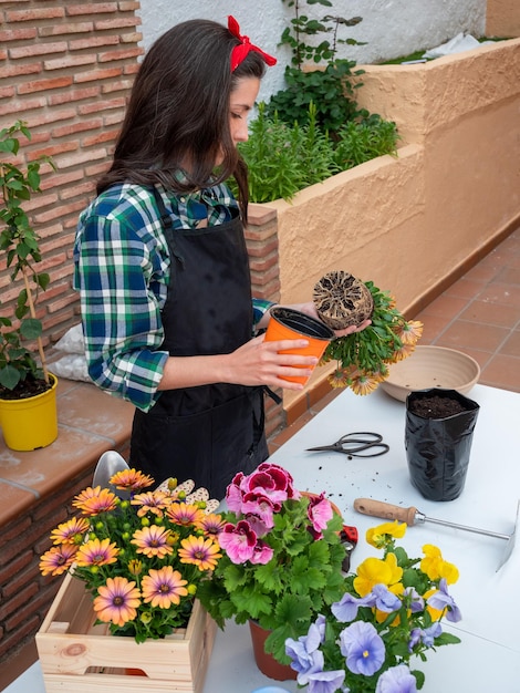 Young Woman Gardening At Home taking a plant out of a pot