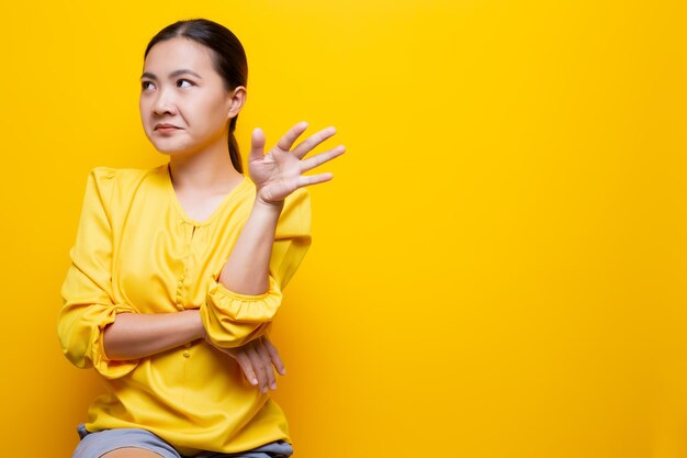 Young woman gesturing against yellow background