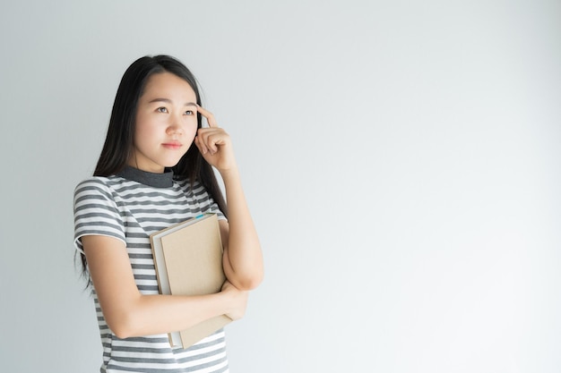 색 배경 에 책 을 들고 몸짓 을 하는 젊은 여자