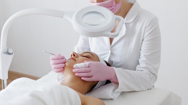 Young woman gets facial cleansing in a cosmetologist's office Skin cleaning at beauty salon