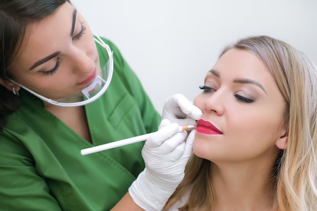 Young woman gets makeup. Lip tattoo in a beauty salon.