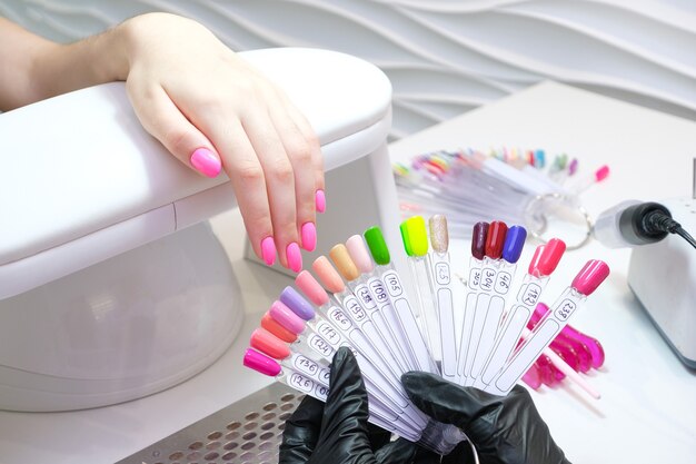 Young woman gets a manicure in the salon. applying shellac to the nails. pink color