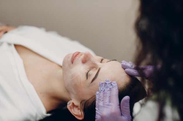 Young woman getting face massage with cosmetics cream in beauty spa